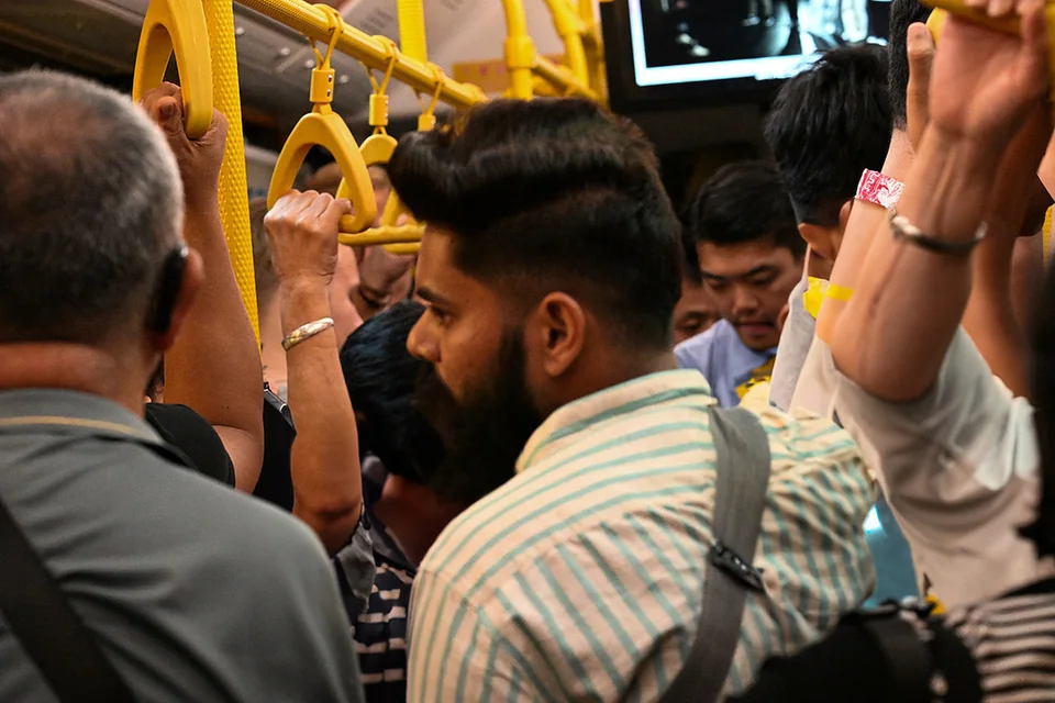 Passengers standing together beneath yellow hand straps