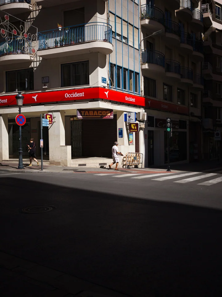 Pedestrians crossing light and shadow at a street corner