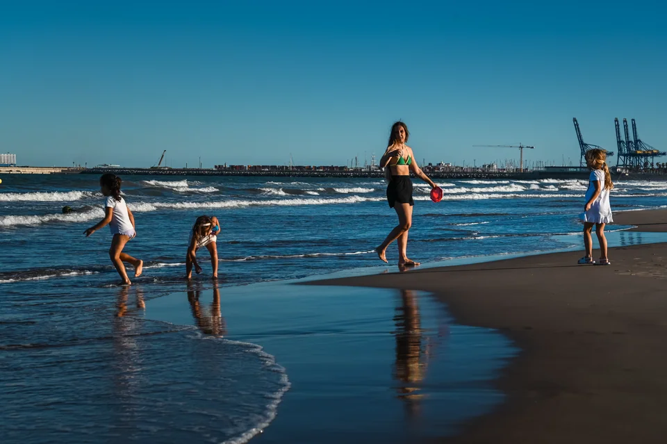 People playing beside the waves on a sunlit beach