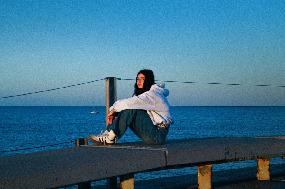 A woman seated by the sea in the evening light